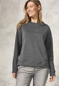 Sudadera gris oscuro de manga larga, corte holgado, con ribete en el dobladillo y logo bordado en el pecho. Textura suave y lisa.