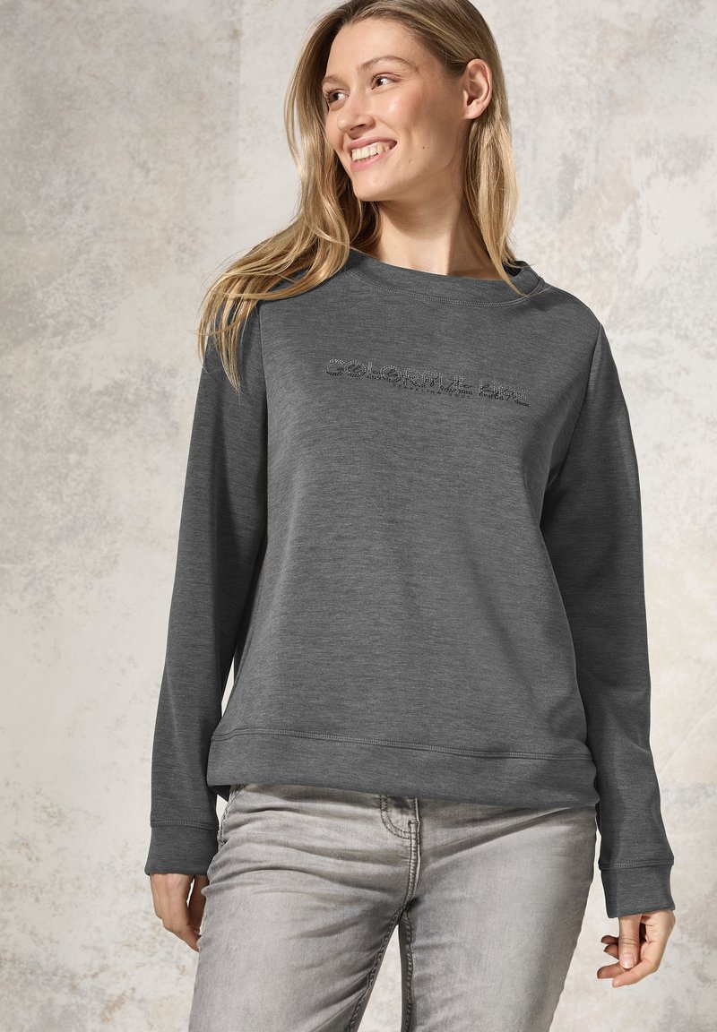 Sudadera gris oscuro de manga larga, corte holgado, con ribete en el dobladillo y logo bordado en el pecho. Textura suave y lisa.