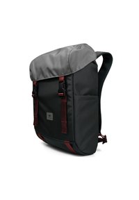 Mochila negra con tapa superior gris, correas rojas ajustables y hebillas seguras. Presenta una tela texturizada y un parche de logo en la parte frontal.