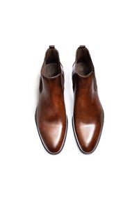 Brązowe skórzane botki za kostkę o gładkim wykończeniu, z elastycznymi bocznymi panelami, pętlami do zakupu i spiczastymi noskami, na białym tle.