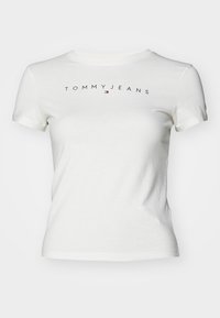Bílá bavlněná tričko s krátkým rukávem. Na hrudi je vytištěný nápis "TOMMY JEANS" v černé barvě a malá značka v červené a modré barvě.