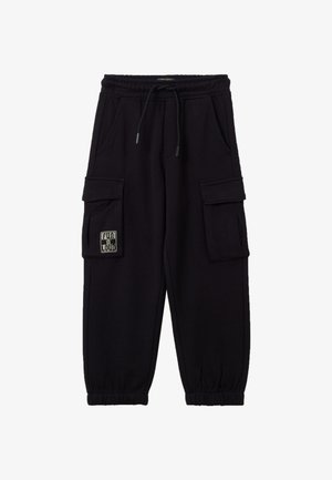 Schwarze Cargo-Hosen aus weichem Stoff mit elastischem Bund, Seitentaschen und einem Patch am linken Bein mit Textdesign.