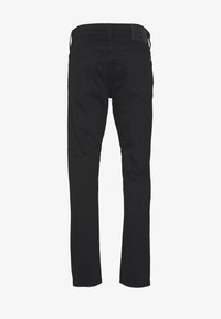 Jeans de mezclilla negra con un corte ajustado, que cuentan con una cintura, dos bolsillos traseros y una textura suave. Vista posterior mostrada.