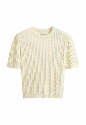 Cremefarbener, kurzärmeliger Kabelstrickpullover mit rundem Ausschnitt sowie geripptem Saum und Bündchen, mit einem kleinen Etikett im Kragen versehen.