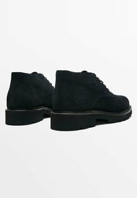 Svarta mockaankelstövlar har en slät yta, rund tå, snörning och kraftiga gummisulor för bra grepp.