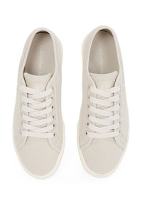 Beige Calvin Klein veterschoenen van canvas met witte zolen, gezien van boven, paar naast elkaar op een witte achtergrond.