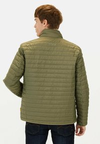 Oliven grøn isoleret jakke med quiltet design, høj krave og subtil branding på ryggen. Ærmerne har syede paneldetaljer.