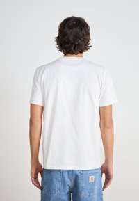 White short-sleeve T-shirt made of cotton, featuring a round neckline and a plain design, shown from the back with denim pants.
