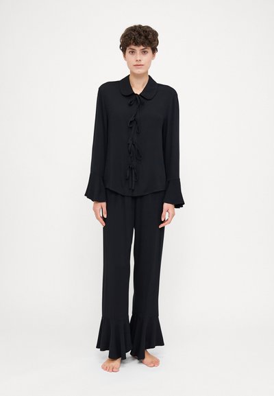 Sæt af sort loungewear bestående af en langærmet top med krave og bånddetaljer, parret med bukser med brede ben.