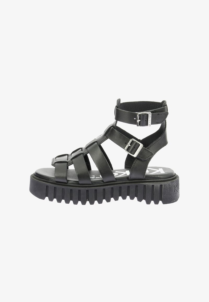Sandalias de cuero negro con tiras, que cuentan con una suela de goma gruesa, múltiples tiras cruzadas y hebillas ajustables en el tobillo.