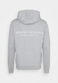 Felpa grigia con cappuccio, con la scritta "ARMANI EXCHANGE MILANO / NEW YORK" in bianco centrata sul retro. Materiale in cotone.