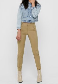 Ljusa blå korta denimjacka med knappstängning, i kombination med åtsittande tanbyxor och beige ormskinnsankelboots.