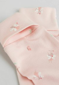 Lyserøde bomuldssokker med fe- og blomsterprint. Stoffet er blødt med en glat tekstur og en opfoldet kant øverst.