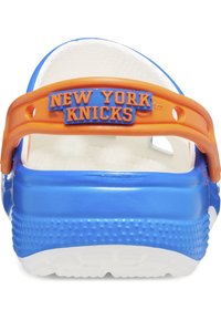 Zoccoli blu e bianchi con una base testurizzata, dotati di una fascia arancione e lettering in rilievo "NEW YORK KNICKS" sul retro.