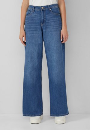 Jeans a gamba larga in denim di media tonalità. Presentano un vita alta, tasche frontali e una chiusura a bottone classica. Tessuto testurizzato con dettagli di cucitura.
