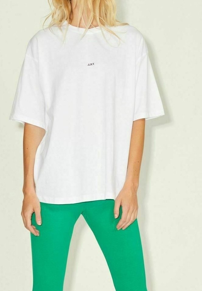 White oversized T-shirt featuring a small black logo in the center, paired with bright green fitted leggings. Smooth fabric texture.
