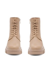 Beżowe skórzane botki za kostkę o teksturowanym wykończeniu, z wiązaniem z przodu i zamkiem błyskawicznym z boku. Grube gumowe podeszwy z wzorzystym bieżnikiem.
