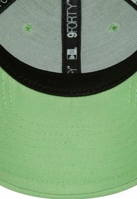 Grüne 9FORTY-Cap aus strukturiertem Stoff mit schwarzem Schirm und Innenseite, flachem Stitching und gemustertem Innenfutter.