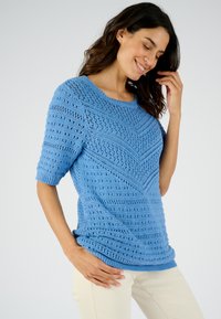 Maglione lavorato a maglia di colore azzurro chiaro con un motivo a zigzag testurizzato, maniche corte e scollatura a girocollo. Materiale morbido e traspirante.