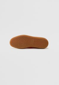 Talpă de pantof din cauciuc cu un model de tread evidențiat prin forme circulare și linii; colorată în nuanță de bej cu o textură netedă.