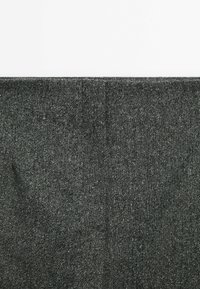 Tissu gris avec une texture tissée subtile et de légères lignes de pli sur un fond blanc uni.