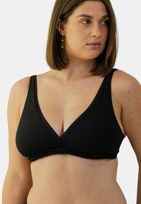 Bralette noir en tissu texturé, avec un décolleté en V profond et des bretelles larges. La construction sans coutures offre confort et soutien.