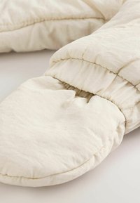 Vita vadderade handskar i kviltad design tillverkade av mjukt tyg. Har rynkade handledsmuddar och en slät, lätt glänsande yta.