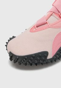 Lichtgewicht sportschoen met een bovenwerk van roze mesh, een gestructureerde zwarte rubberen buitenzool met spikes en een roze elastische band voor een stevige pasvorm.