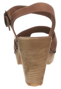 Sandale en suède marron avec un talon en bois, bride ajustable et couture décorative le long des bords. Vue arrière.