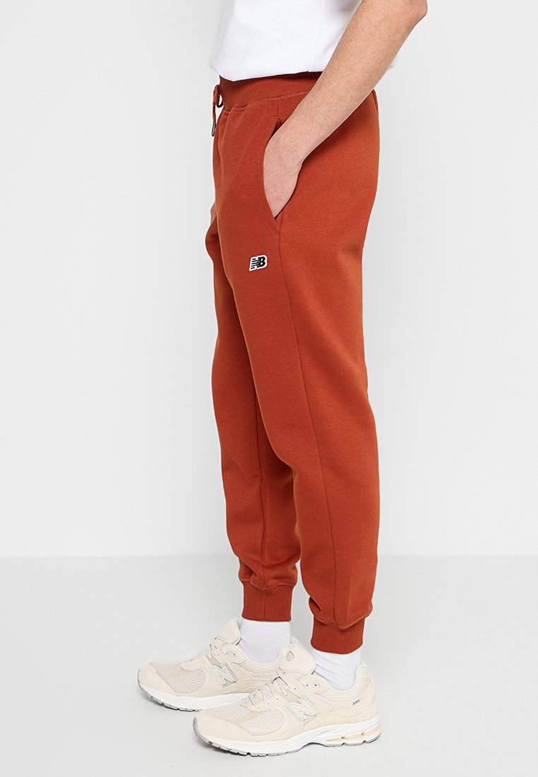 Roodkleurige joggerbroeken van zacht materiaal, met zijzakken, een strakke boord bij de enkels en een klein logo op de linker bovenbeen.