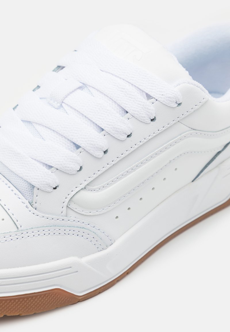 Witte leren sneakers met een gladde textuur, voorzien van platte witte veters, geperforeerde accenten en een gumrubberen zool. Eenvoudig ontwerp en stikseldetails.