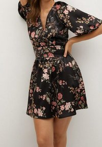 Vestido negro con estampado floral que presenta un escote en V profundo, mangas abullonadas y una cintura ajustada. La tela tiene una textura suave con patrones florales coloridos.