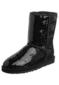 Bota de tobillo negra con lentejuelas, con puntera redonda y un forro interior suave. La textura incluye lentejuelas brillantes con un patrón de camuflaje.