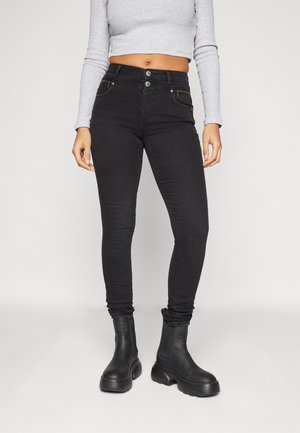 Jeans skinny negri cu talie înaltă, două buzunare frontale și fermoare aurii. Material texturat asortat cu cizme negre până la gleznă.