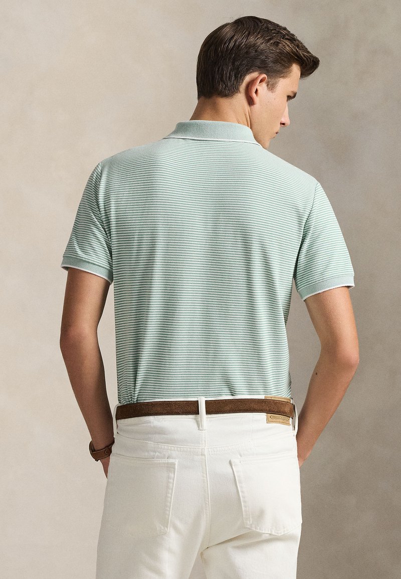 Light green striped polo shirt with short sleeves and a collar, paired with white trousers and a brown belt. Textured fabric visible.