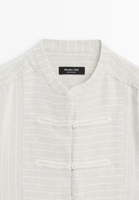 Jasnoszara, fakturowana koszula z kołnierzem stójką, z pionowymi paskami, zapinana na dwa guziki, z metką marki "Massimo Dutti".
