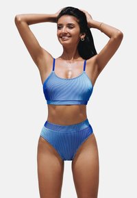 Ensemble de bikini à rayures bleues avec un haut court et un bas taille haute. Fabriqué en tissu lisse et brillant avec des bretelles réglables.