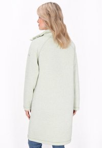 Cappotto lungo in fleece verde chiaro con colletto alto e bottoni a pressione. Presenta un tessuto texturizzato e polsini a coste. Visualizzazione della vista posteriore.