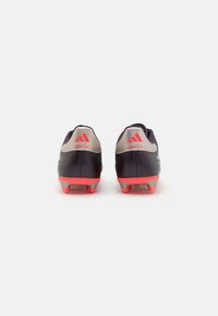 Black and gray soccer cleats with a smooth texture, featuring bright pink accents and molded studs for traction. Heel has logo detail.