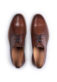 Brune lædersko med perforeret design, flade snørebånd og kontrasterende såler. Har en glat finish og diskrete syningsdetaljer.