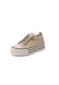 Zapatilla de lona beige de perfil bajo con suela plataforma blanca gruesa que presenta dos rayas negras y cordones redondos en blanco y negro.