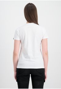 Hvit kortermet t-skjorte med rund hals. Glatt tekstur, tettsittende design. Sorte bukser med lommer og knappdetaljer.