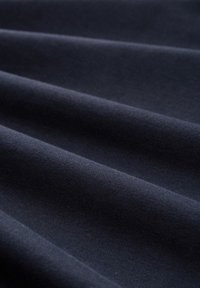 Granatowy materiał o gładkiej teksturze, z delikatnymi fałdami i lekkim połyskiem. Materiał wydaje się lekki i wszechstronny.