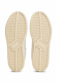 Witte sneakerzool met een textuurpatroon voor grip. "Tommy Jeans"-logo centraal te zien. Ronde vorm met duidelijke loopvlakken.