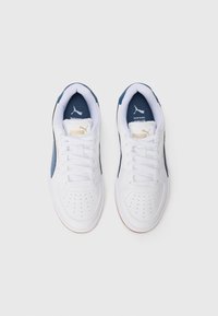 Baskets blanches avec des accents bleu marine, bout perforé et lacets blancs. Présente un logo doré sur la languette et sur le côté. Semelle en caoutchouc.