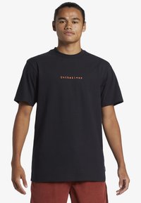 Black cotton t-shirt with short sleeves. Features orange "Quiksilver" logo centered on the chest. Classic crew neckline and relaxed fit.