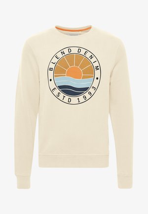 Cremefarvet sweatshirt med et cirkulært grafisk design, der viser en solnedgang og bølger i orange, blå og marineblå. Ribbet på ærmer og kant.