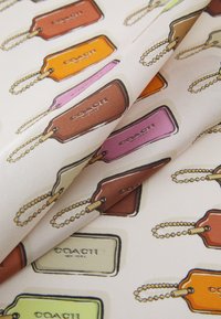 Kuvioitu kangas, jossa on toistuvia kuvastoja värikkäistä kulmikkaista tarroista, joissa on pyöristetyt kulmat ja ketjujaksot, vaalealla taustalla.