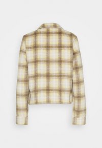 Rutig kort jacka i gula, vita och bruna nyanser. Har en klassisk krage, långa ärmar och strukturerad tyg.