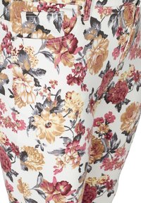 Pantaloni a fantasia floreale con grandi fiori rosa, gialli e viola su sfondo bianco; dotati di tasche e dettagli di cucitura a contrasto.